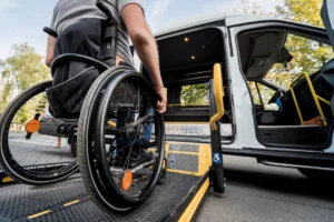 A man in a wheelchair moves to the lift of a specialized vehicle