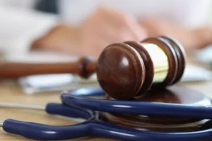 Closeup of judge gavel of stethoscope doctor in background writing notes